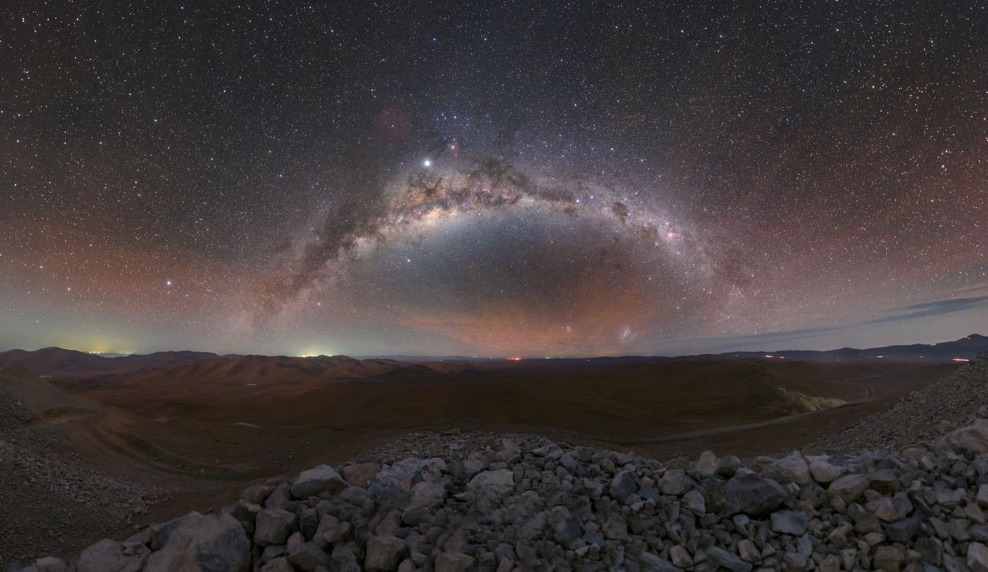 The arch of the Milky Way over desert hills, with pale rocks in the foreground