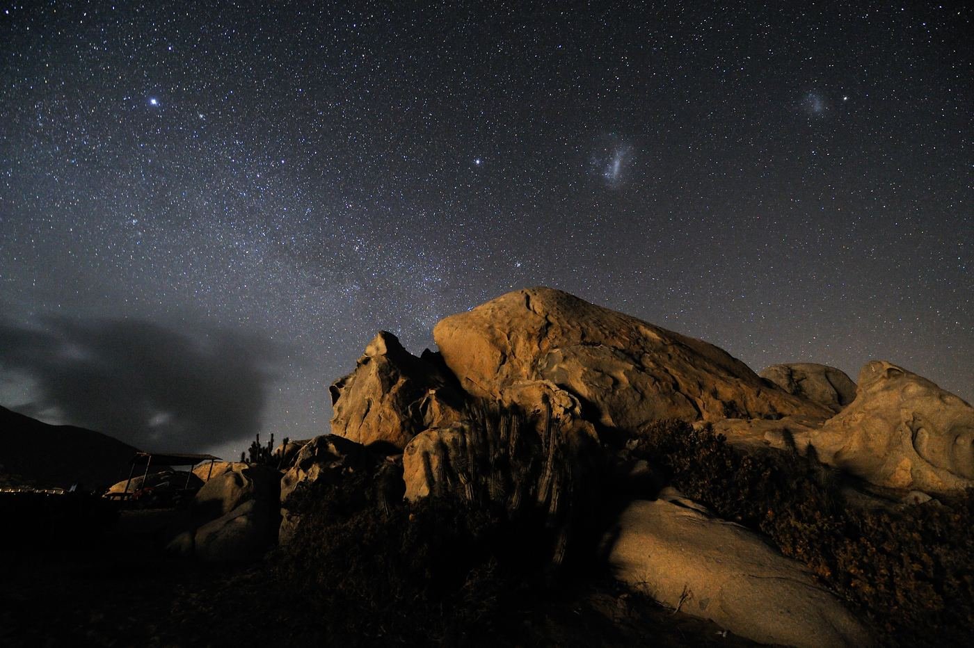 Warmly lit rocks under the Milky Way on a desert coast at night